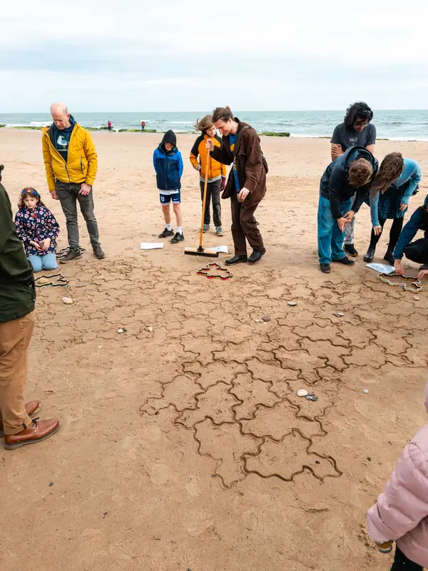 A volunteer using a broom to smooth the sand.