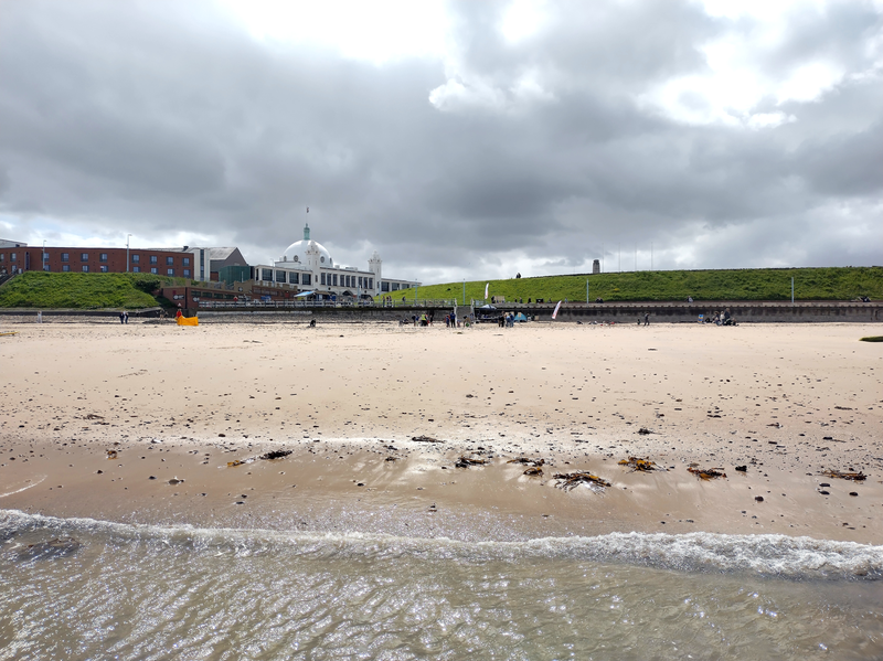 Looking up the beach from the sea. Waves are coming in at the bottom of the frame. The white-domed Spanish City and the beach links are in the background.
