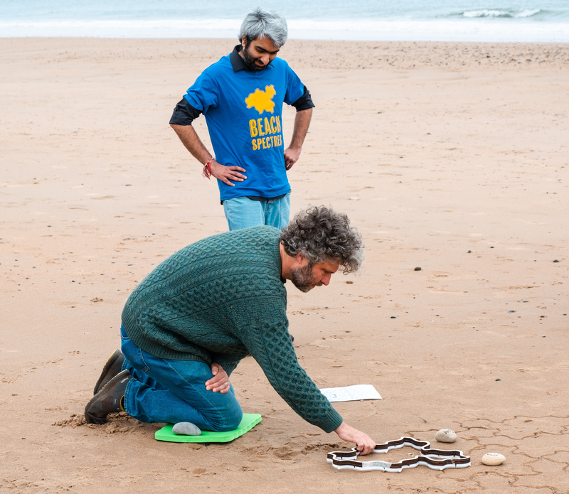 A person positioning a stamper, while a volunteer looks on.