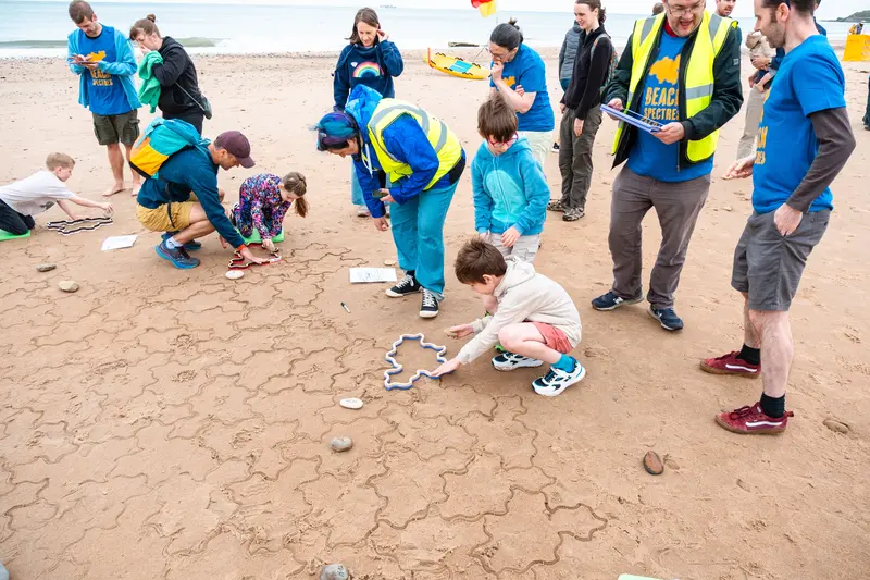 Two children positioning a stamper, with volunteers looking on.