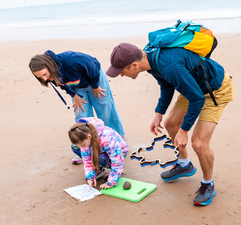 A child and their parents, consulting a printed diagram while holding a Spectre stamper.