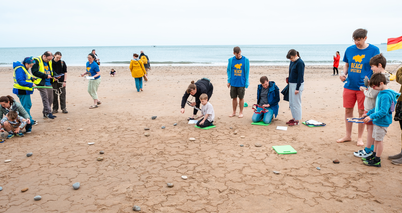 People around the edge of the tiling, kneeling and stamping or standing and thinking.