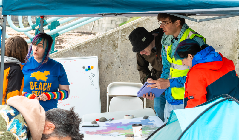 Volunteers gathered in the gazebo, talking to a participant and consulting the map.